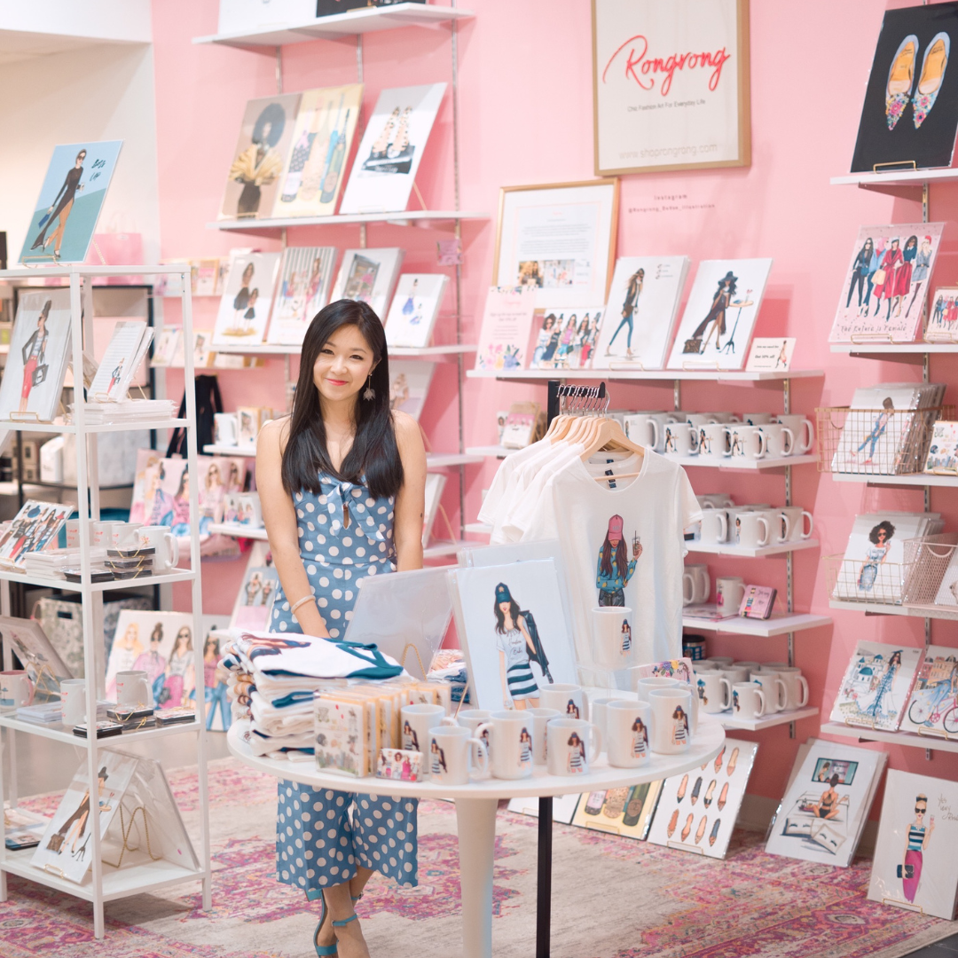 Woman in shop with artwork and merchandise.