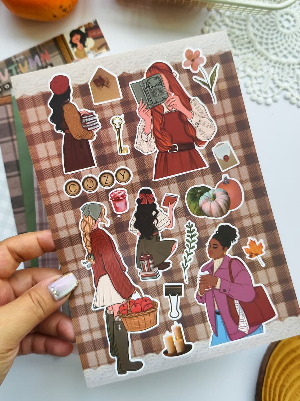 Close-up of the Autumn Moments vinyl sticker sheet showcasing cozy autumn-themed character stickers, pumpkins, coffee, books, candles, and seasonal decorative elements.