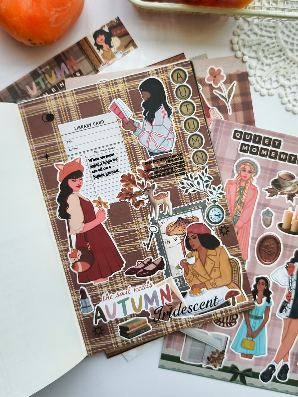 Journal spread decorated with Autumn Moments vinyl stickers featuring plaid backgrounds, library cards, books, woodland accents, cozy girls, and warm fall colors.
