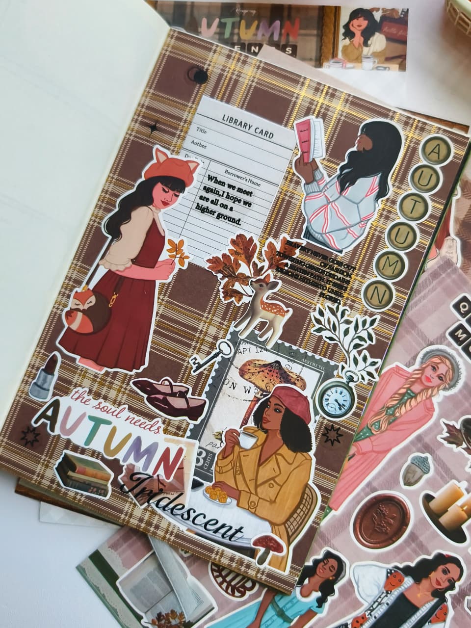 Close-up of a handmade autumn journal page using Autumn Moments vinyl stickers with bookish illustrations, plaid backgrounds, library cards, candles, woodland animals, and cozy seasonal accents.
