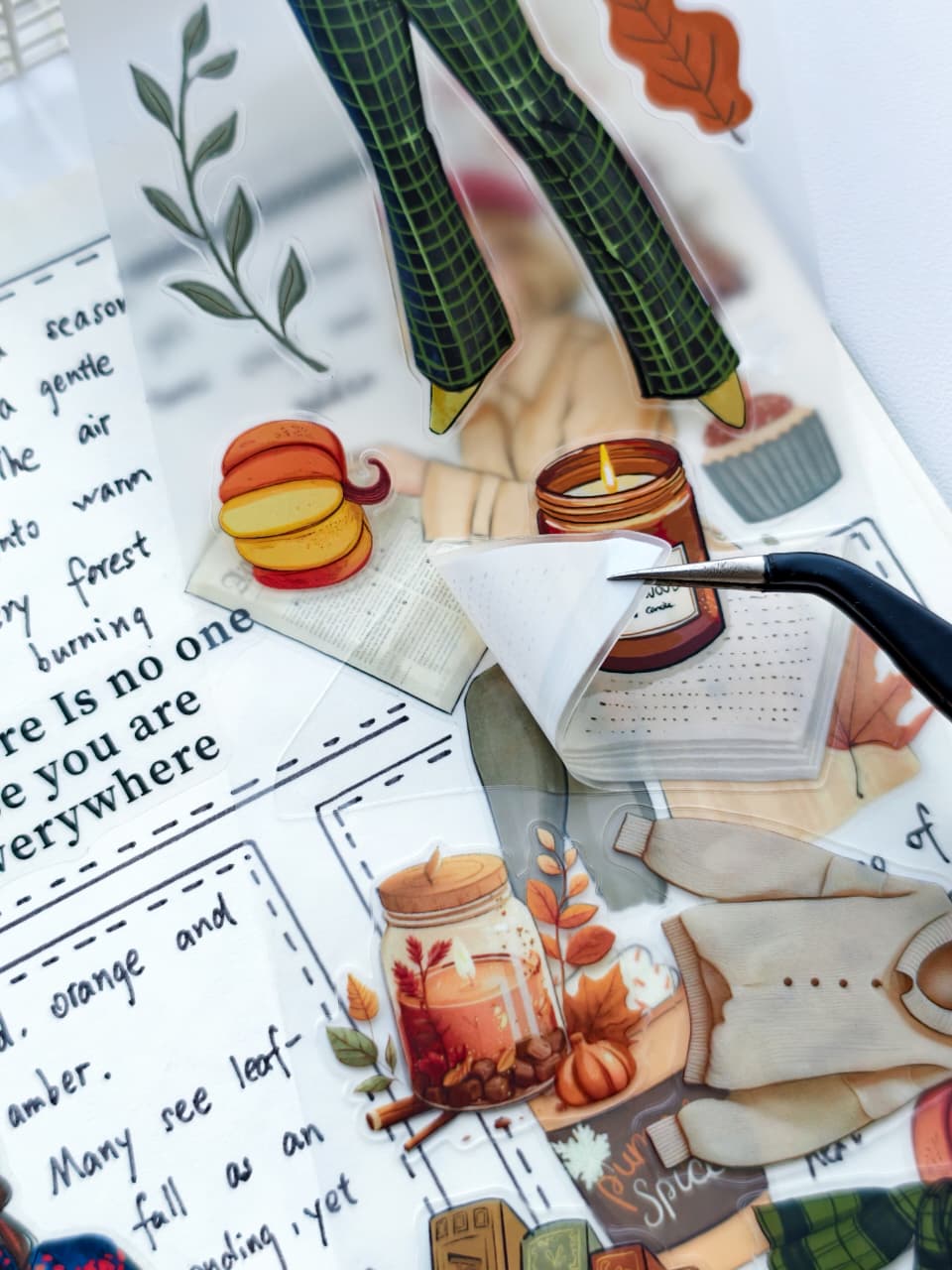 Close-up of Amber Allure pre-cut PET tape showing an easy-to-peel transparent sticker featuring cozy autumn illustrations, candles, books, pumpkins, and fall-themed journaling elements.
