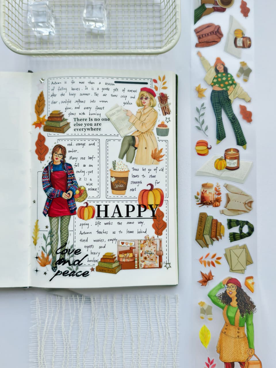 Flat lay of a journal decorated using Amber Allure pre-cut PET tape with transparent autumn stickers including fashion illustrations, pumpkins, candles, books, sweaters, and fall foliage.