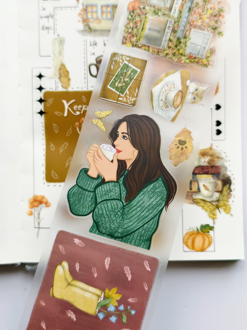 Detailed PET tape designs showcasing a woman sipping coffee, a cozy armchair, autumn leaves, books, cats, butterflies, and charming café-inspired elements on transparent PET material.