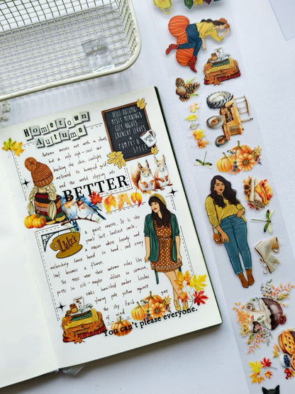 Autumn-themed journal page decorated with pre-cut PET stickers featuring pumpkins, squirrels, autumn leaves, cozy fashion illustrations, and rustic seasonal elements arranged around handwritten journaling.