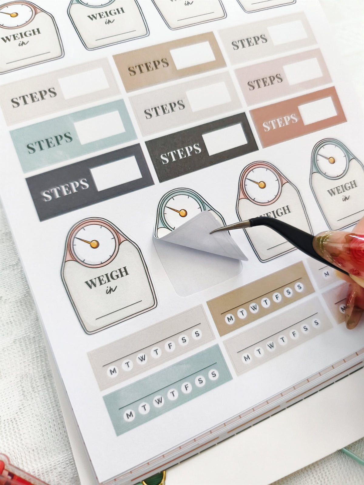 Sticker sheet with 'WEIGH' and 'STEPS' labels being cut out with scissors.