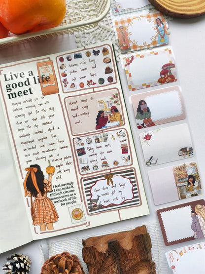 Angled view of a cozy fall journal layout decorated with seasonal illustrations and Autumn Memos Sticky Notes featuring autumn-inspired writable memo designs, pumpkins, mushrooms, books, and cozy café scenes.