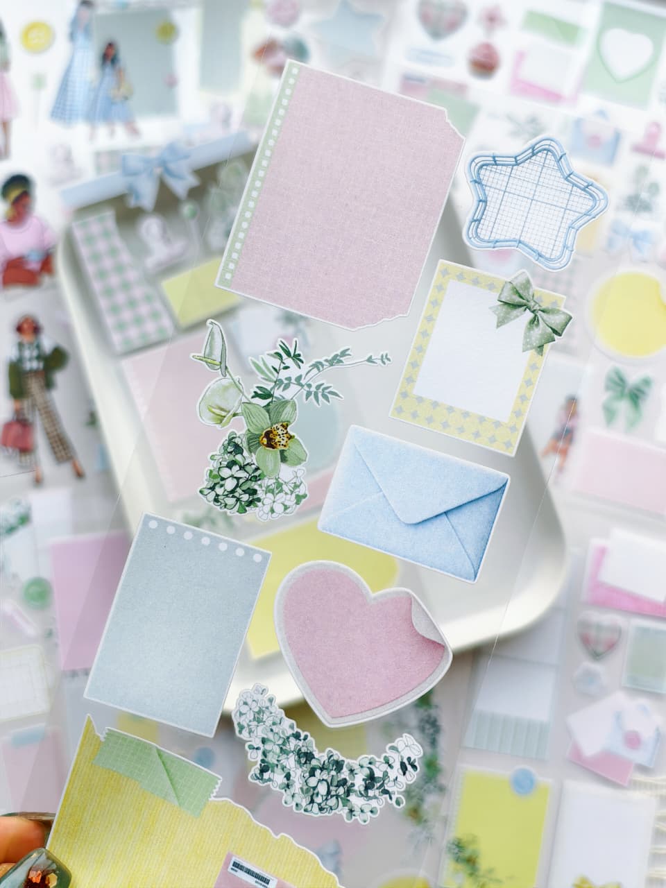 Close-up of transparent pastel stickers with memo cards, envelopes, floral accents, bows, hearts, and soft scrapbook-inspired decorative elements for planners and journals.