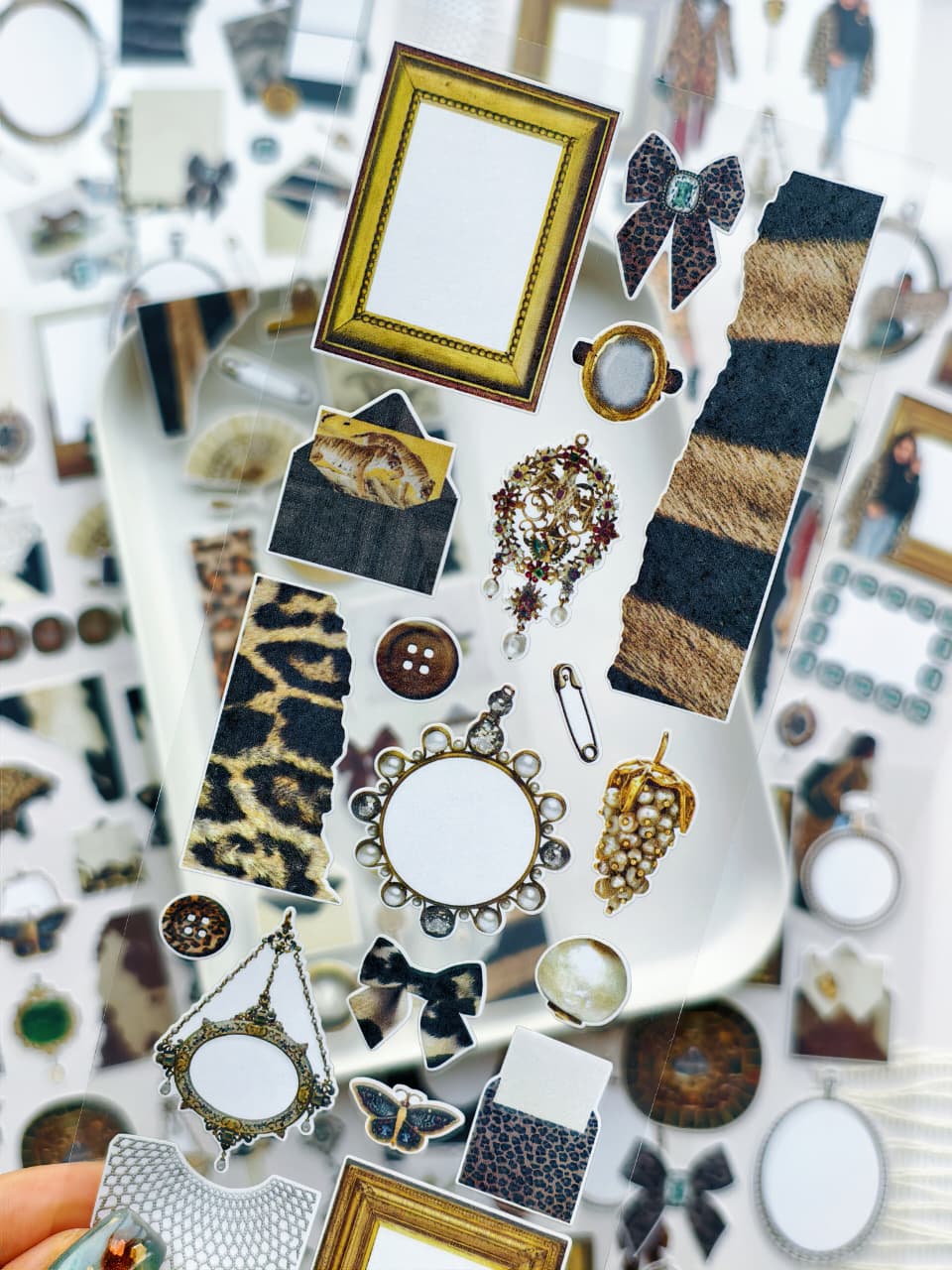 Close-up of transparent stickers with leopard print patterns, ornate gold frames, pearls, bows, butterflies, and vintage decorative elements for journaling and planners.