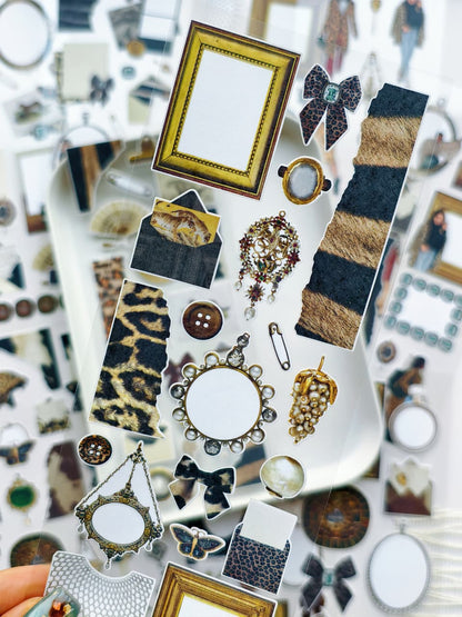Close-up of transparent stickers with leopard print patterns, ornate gold frames, pearls, bows, butterflies, and vintage decorative elements for journaling and planners.