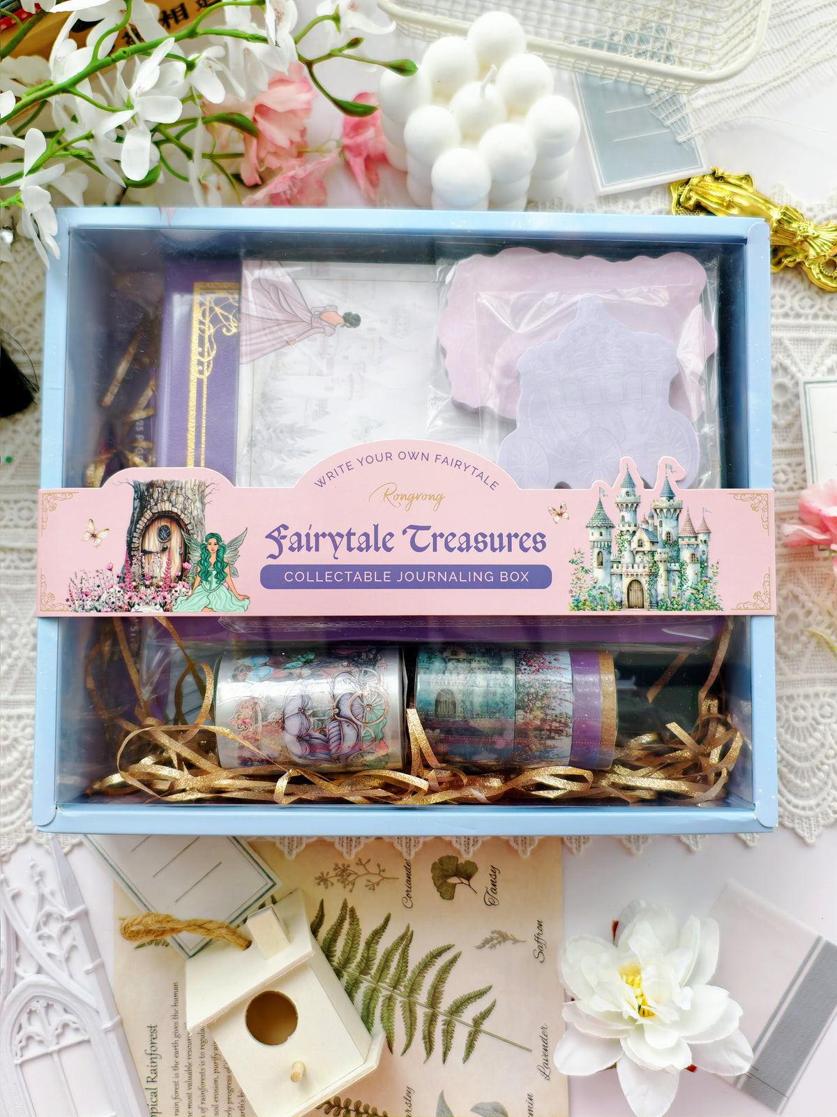 Collectible journaling box with decorative items and 'Fairytale Treasures' packaging on a floral background.