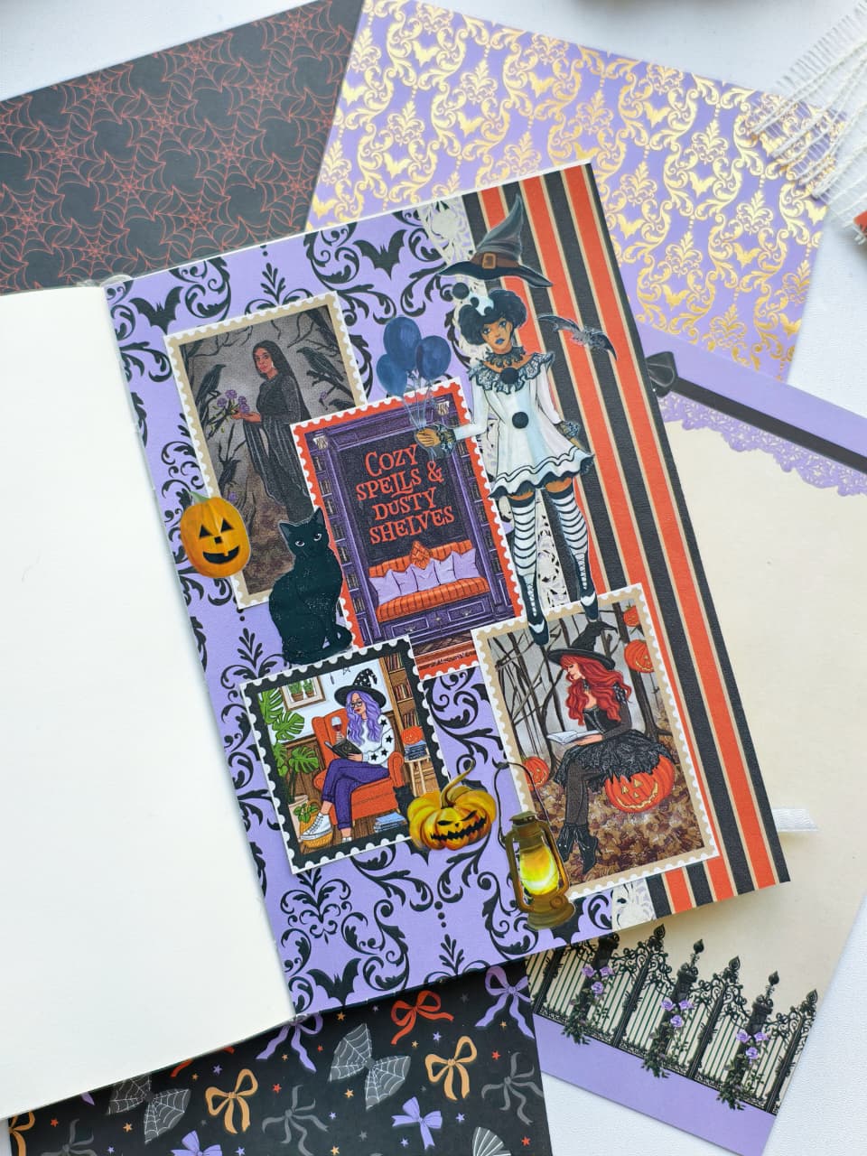 A Halloween-themed scrapbook paper sheet featuring a collage of spooky illustrations, including a witch, black cat, pumpkins, and a ghostly figure, layered over a purple damask pattern. The sheet is displayed on top of other coordinating patterned papers.
