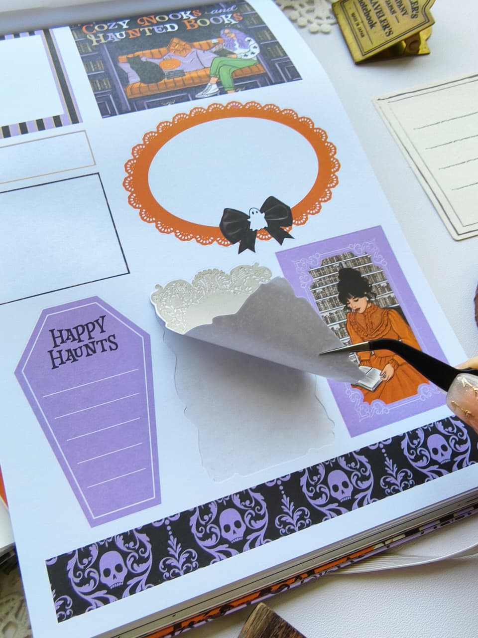 Close-up of the Happy Haunts Sticker Book showing a premium kiss-cut functional Halloween sticker being peeled from the page, featuring spooky labels, decorative frames, and bookish Halloween accents.