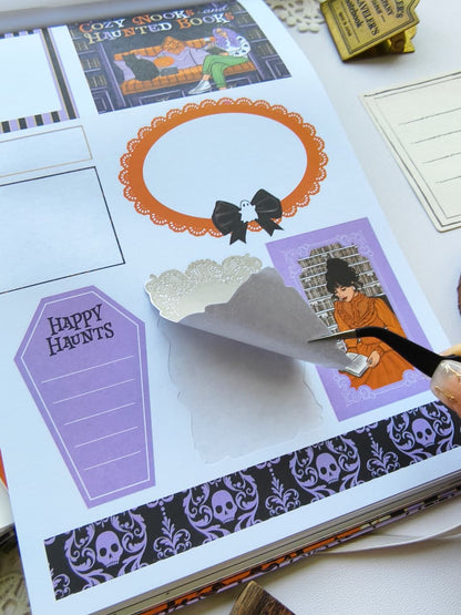 Close-up of the Happy Haunts Sticker Book showing a premium kiss-cut functional Halloween sticker being peeled from the page, featuring spooky labels, decorative frames, and bookish Halloween accents.