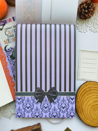 Decorative scrapbook paper page featuring purple and black striped patterns, gothic damask, and black bow accents designed for Halloween journals and scrapbook layouts.