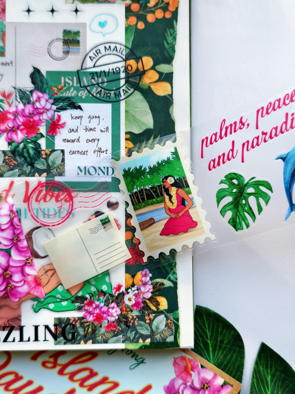 Close-up of a tropical journal spread created with the Island Daydreams Monthly Planning Kit featuring floral stickers, island-inspired ephemera, postage stamp designs, lush greenery, and vibrant pink Hawaiian-themed illustrations.