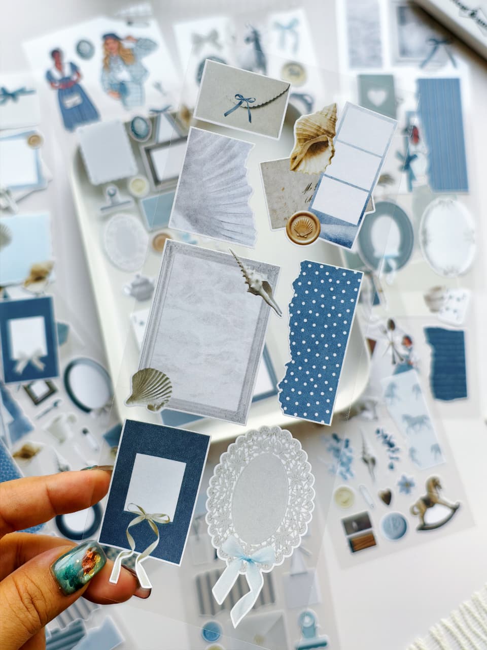 Collection of decorative paper elements including cards, stickers, and embellishments on a light background.