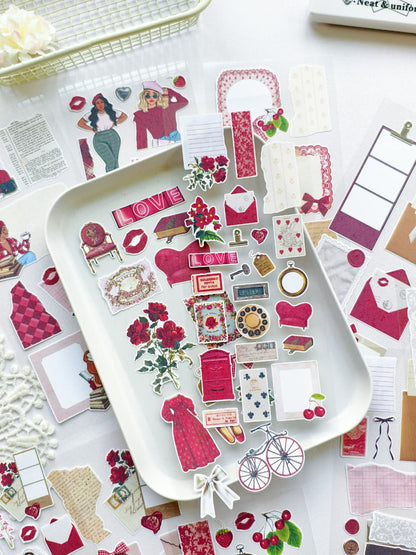 Vintage-inspired ephemera sticker sheet set featuring romantic red and pink tones, feminine fashion illustrations, florals, cherries, bicycles, beauty accessories, and layered decorative stickers styled on a white tray for journaling, planners, and scrapbooking.