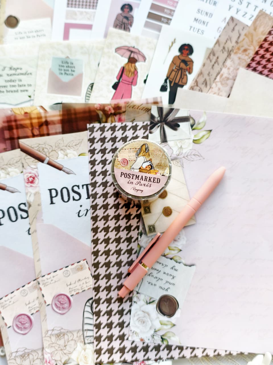 Postmarked in Paris, the PET tape roll displayed on layered vintage-inspired papers with floral details, houndstooth patterns, handwritten letters, and a blush pink pen.