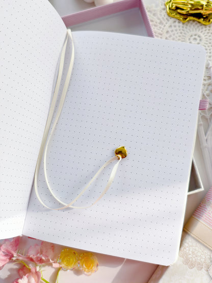 Bullet journal with dotted pages and ribbon bookmark with gold charm, perfect for journaling and planning